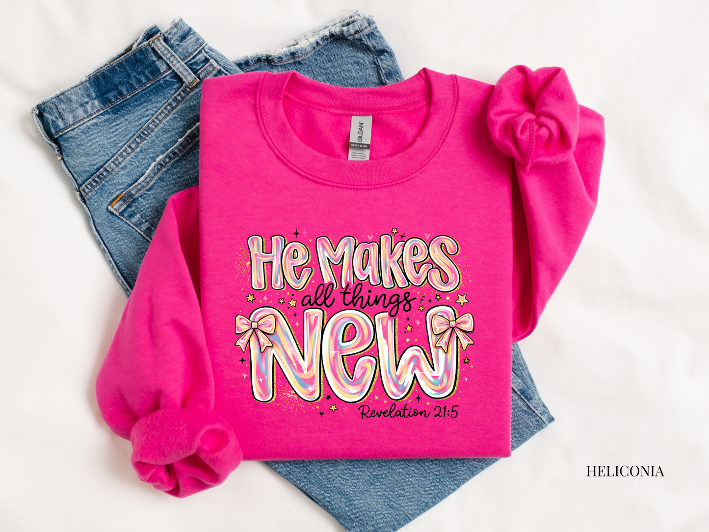 Pink sweatshirt with 'He makes all things new' text on a white background