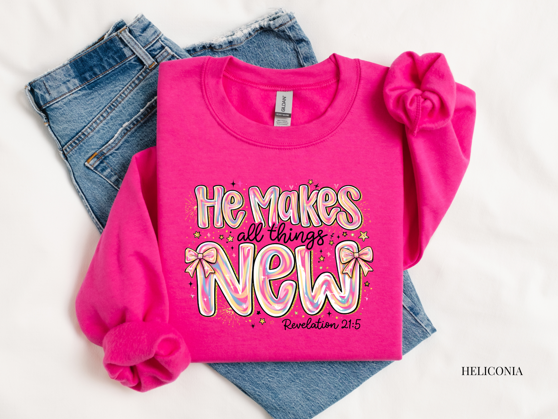 Pink sweatshirt with 'He makes all things new' text on a white background