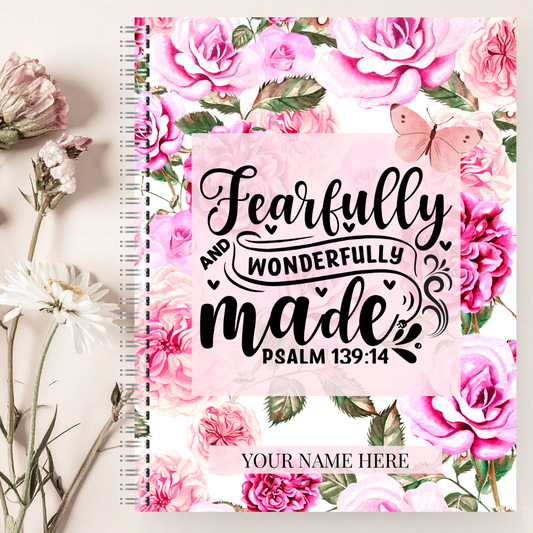Notebook with floral design and 'Fearfully and Wonderfully Made' text on a light background