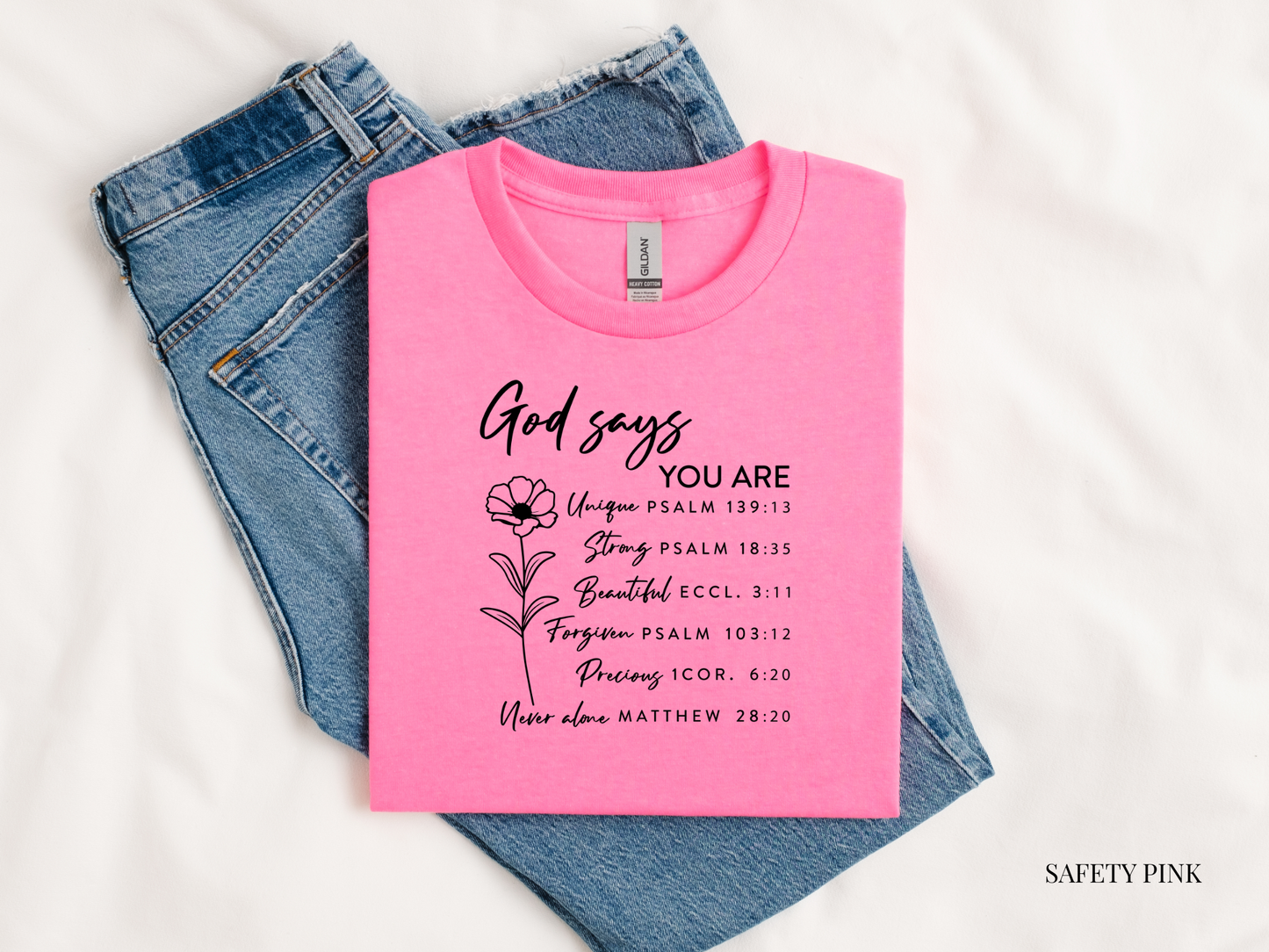 Pink t-shirt with motivational text and denim jeans on a white background