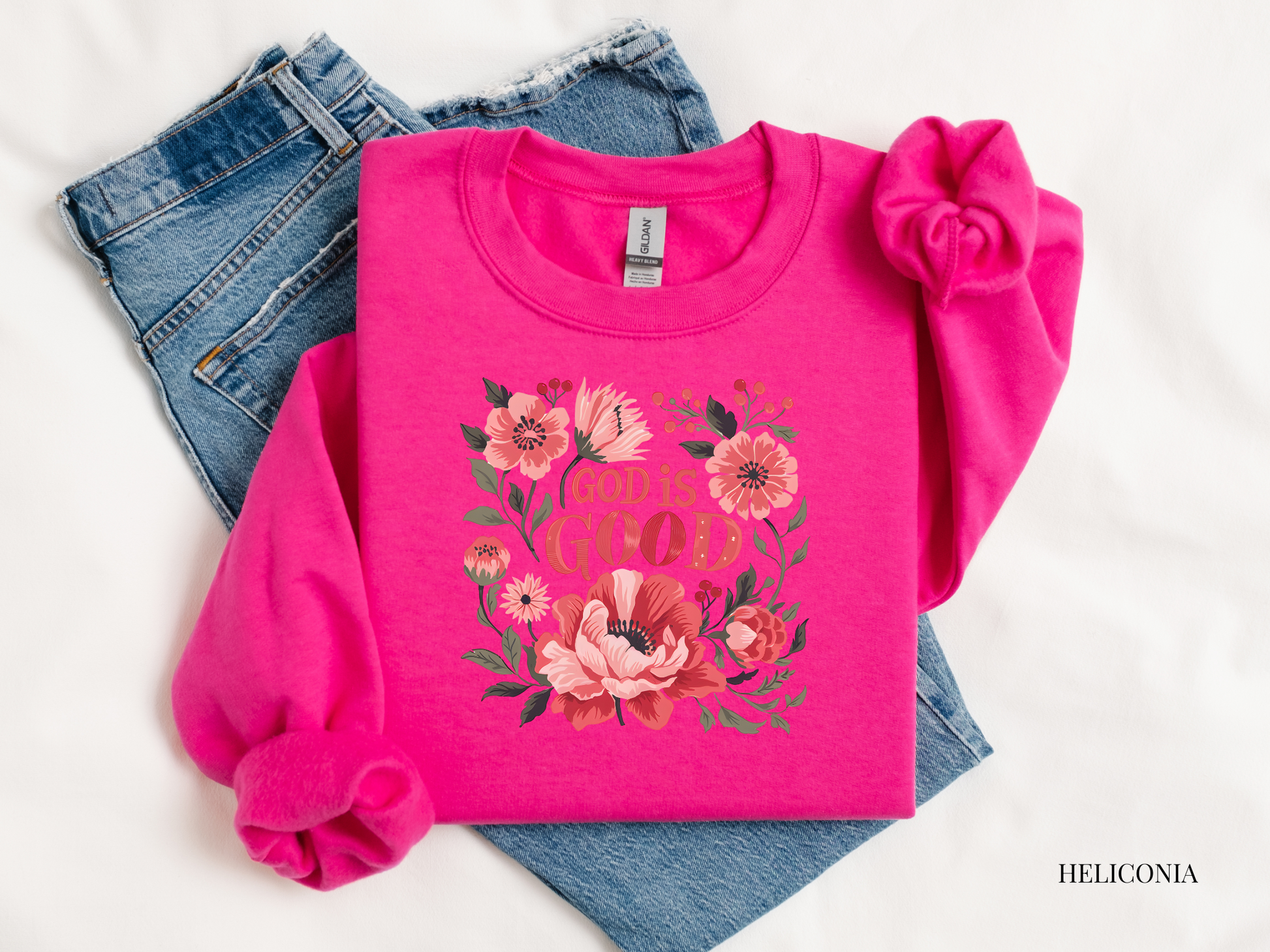 Pink sweatshirt with floral design and text, paired with jeans on a white background