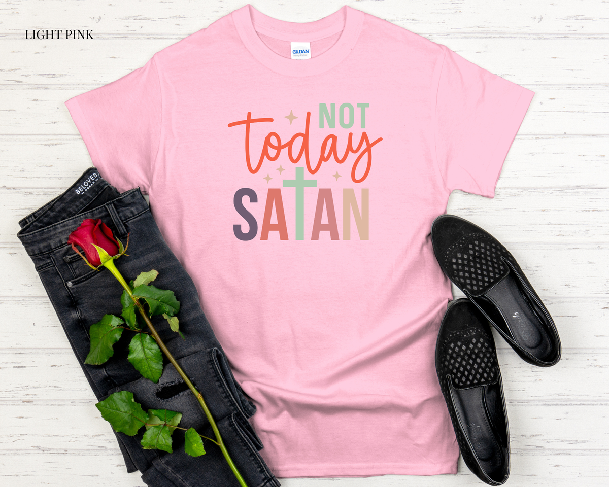 Pink t-shirt with 'Not Today Satan' text, black jeans, black shoes, and a red rose on a light wooden surface.