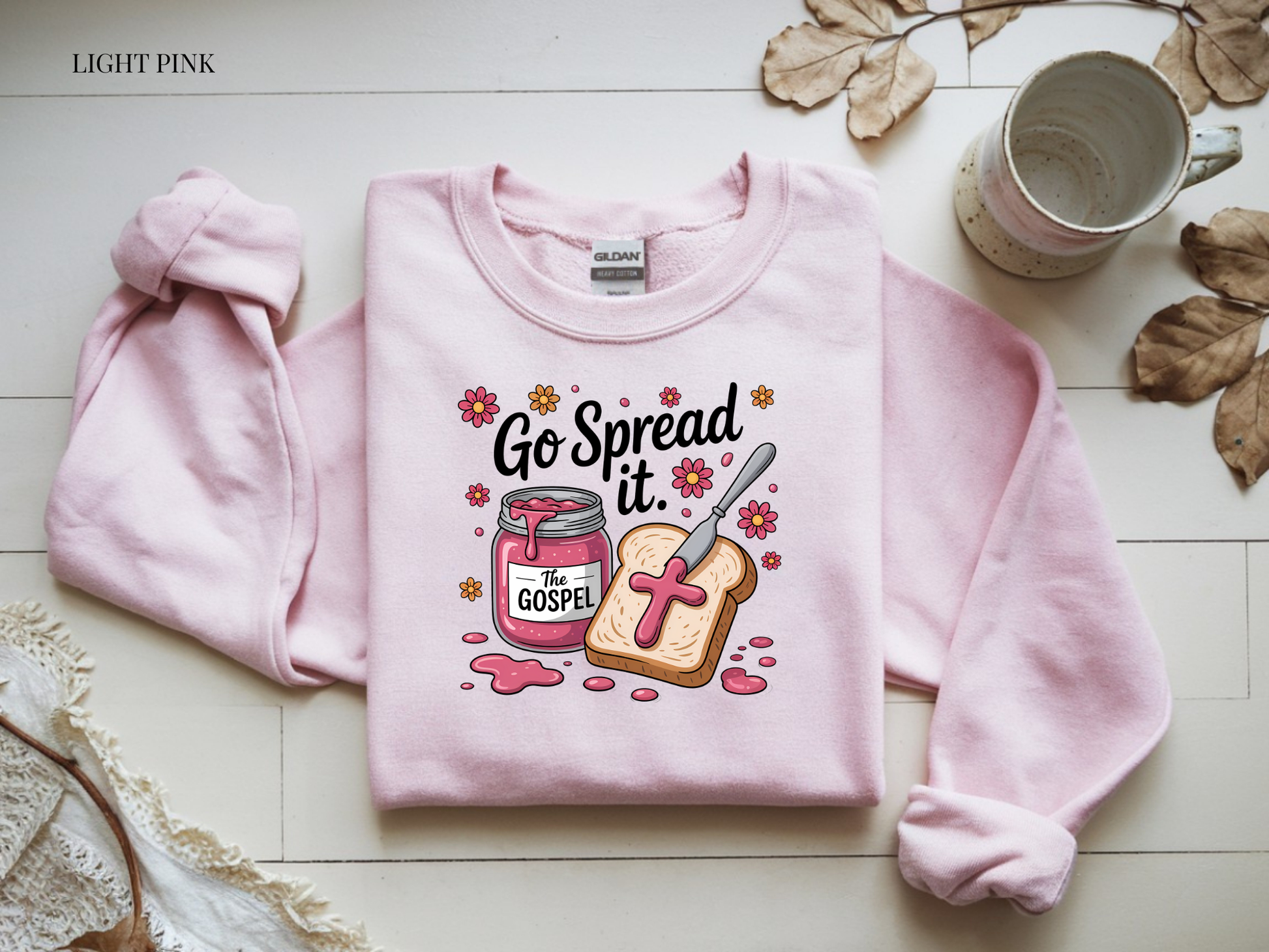 Pink sweatshirt with graphic design on a light wooden surface
