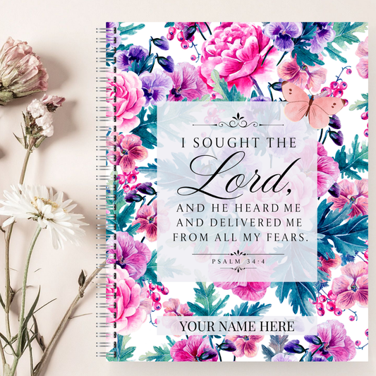 Floral notebook with motivational quote and space for name, surrounded by flowers on a light background