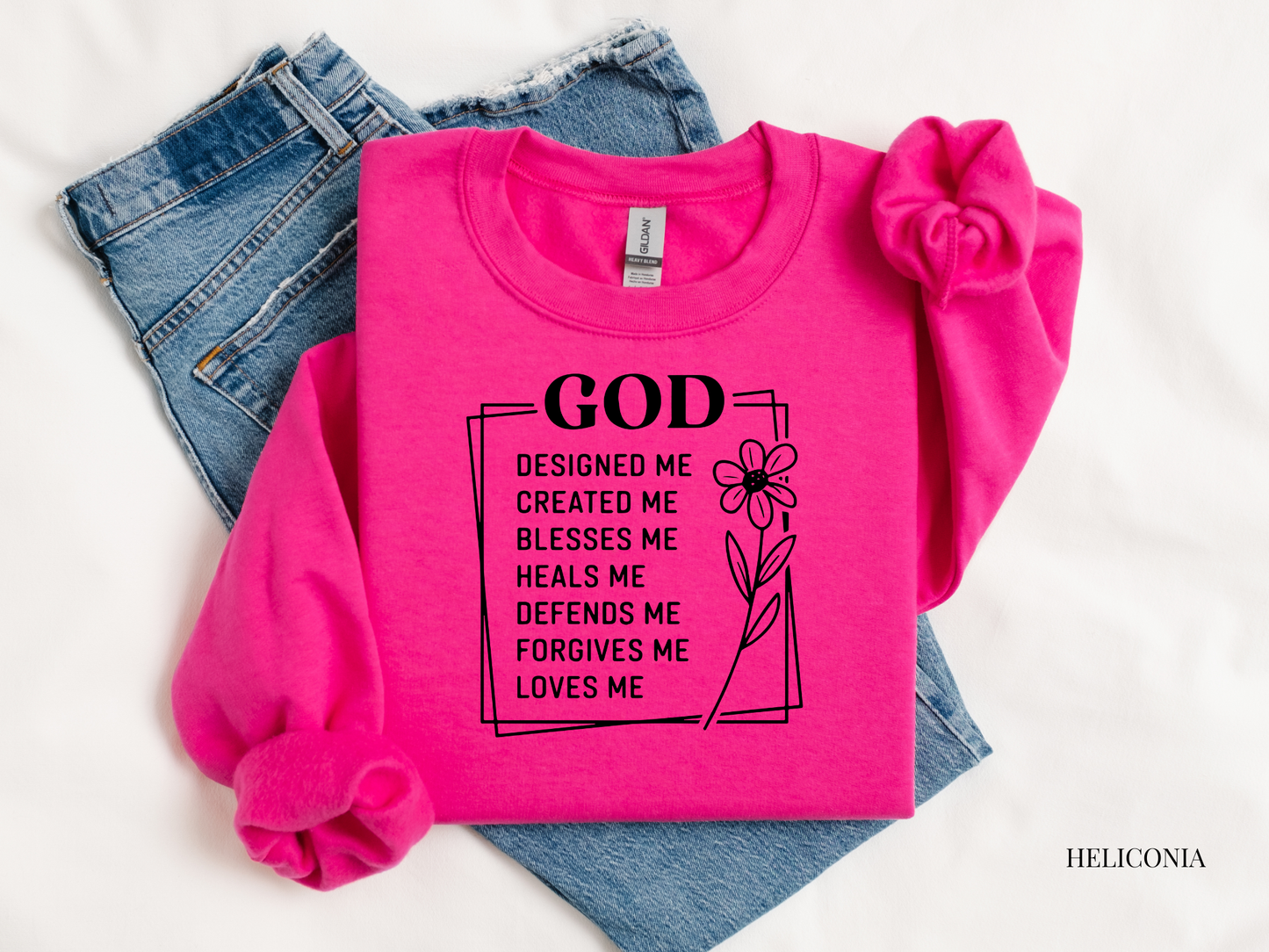 Pink sweatshirt with text and denim jeans on a white background