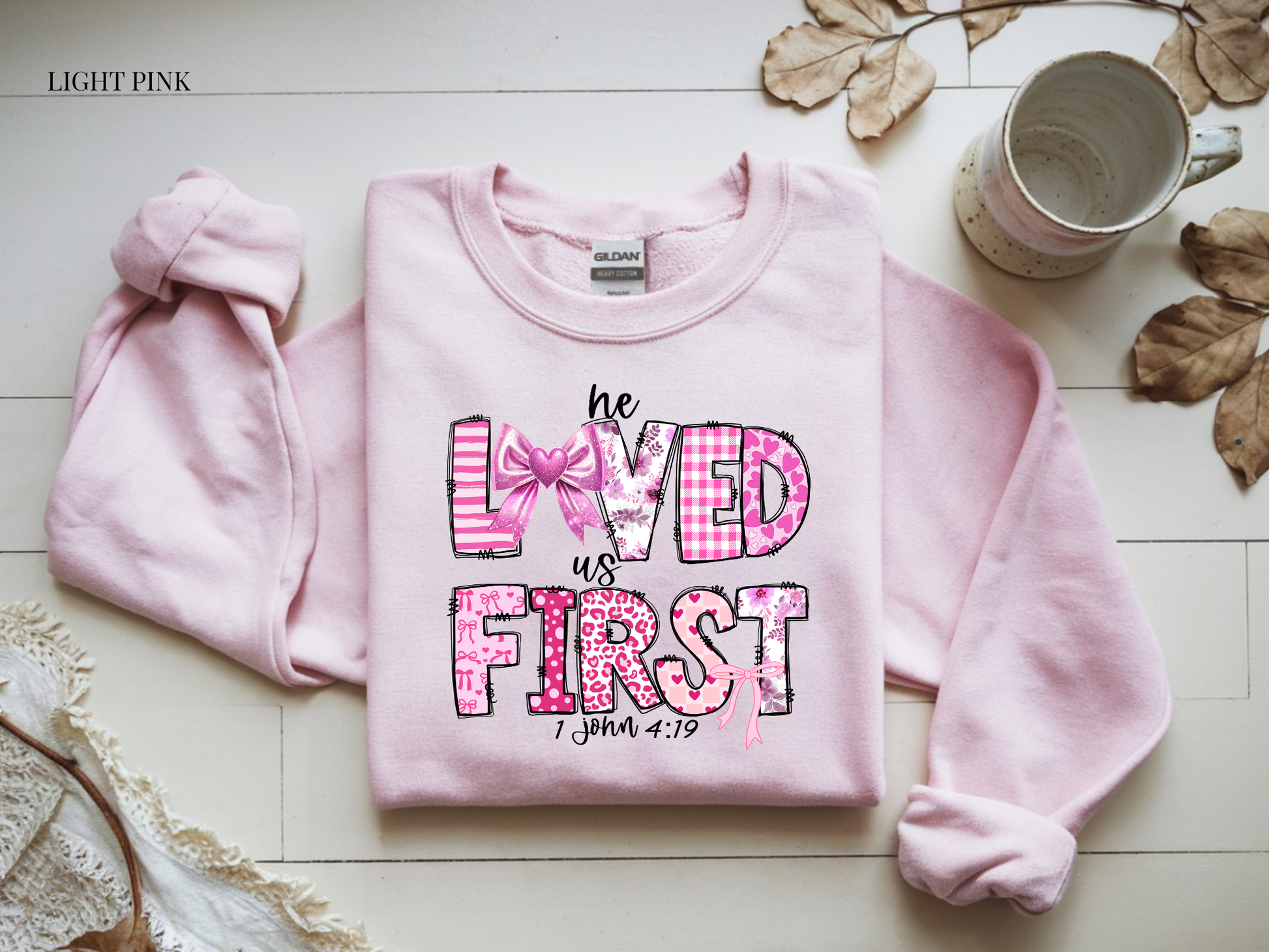 Light pink sweatshirt with text and graphics on a wooden surface