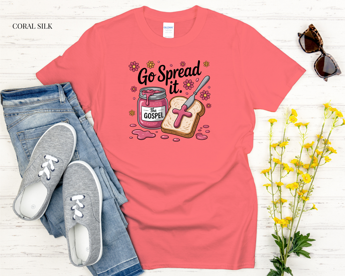Coral t-shirt with 'Go Spread it. Go Gospel' design, paired with jeans and sneakers on a light wooden surface.