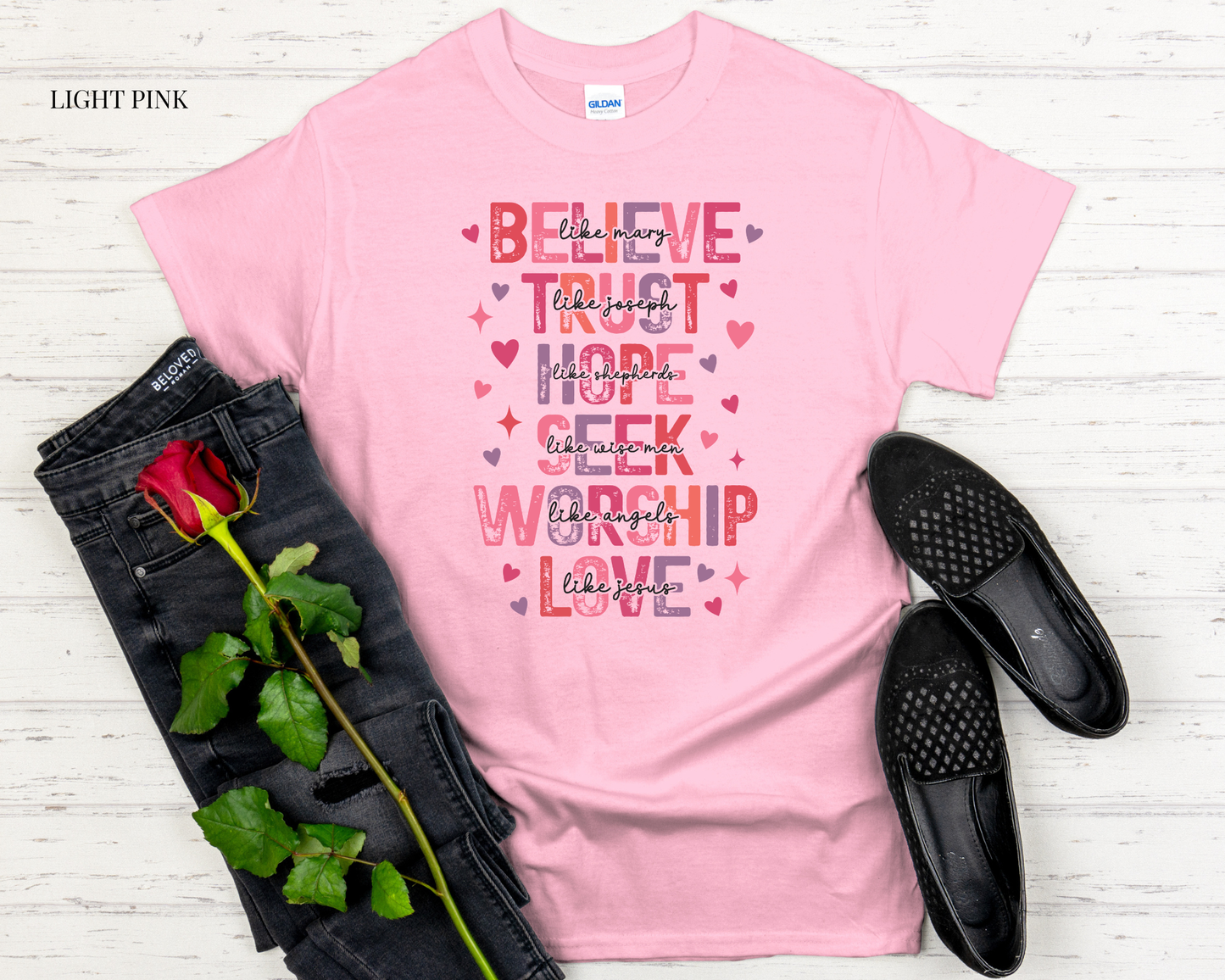 pink t shirt with design with black jeans and white background