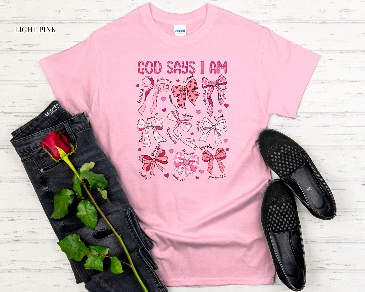 Light pink t-shirt with graphic design and accessories on a wooden surface