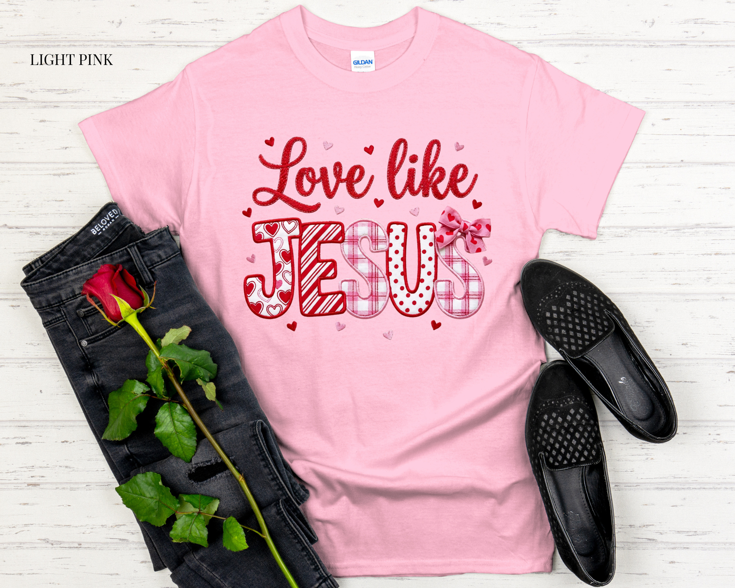 pink t shirt with design with black jeans and white background