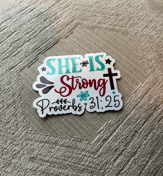 Sticker with 'SHE IS Strong Proverbs 31:25' text on a textured surface