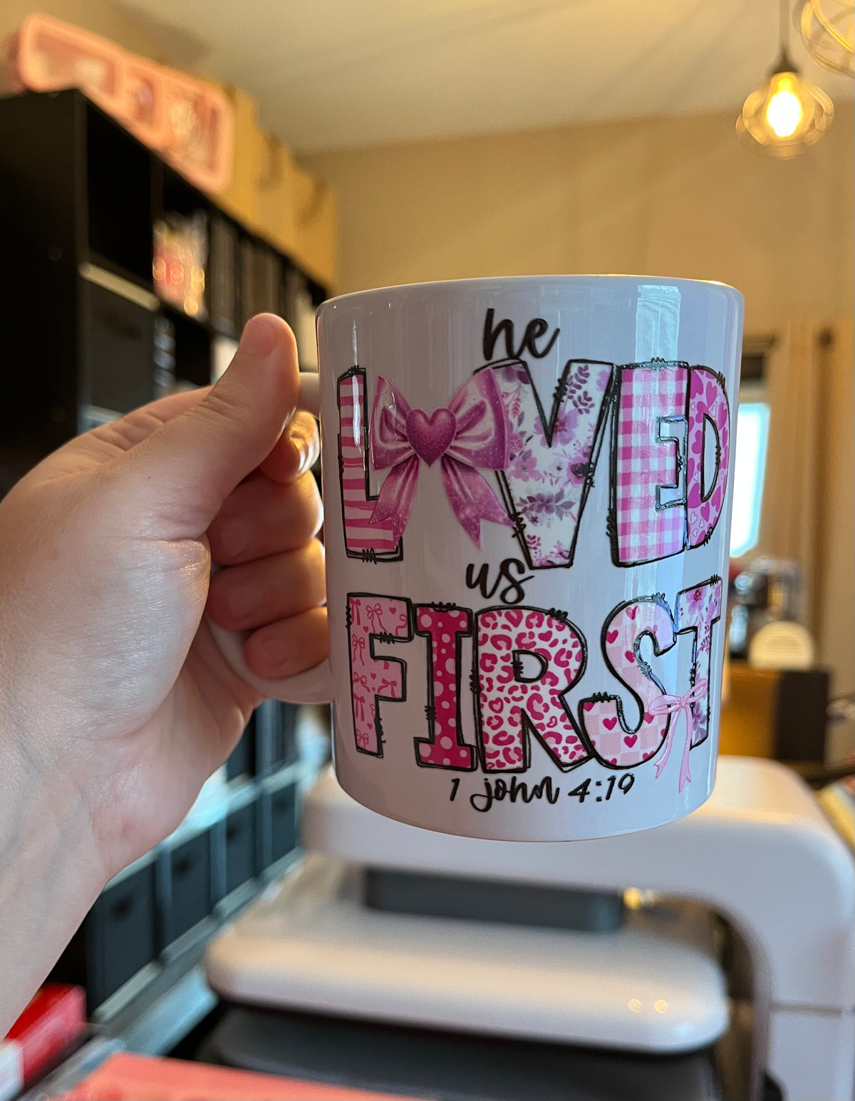 Hand holding a mug with decorative text and design in a kitchen setting