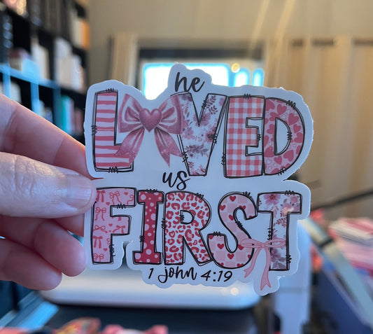 Sticker with decorative text and patterns held by a hand, with a blurred indoor background.