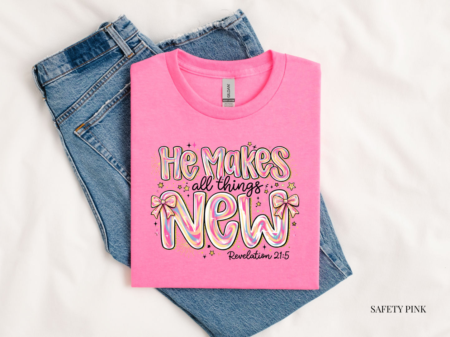 he makes all things new revelation 21:5 pink tshirt against blue jeans against white background