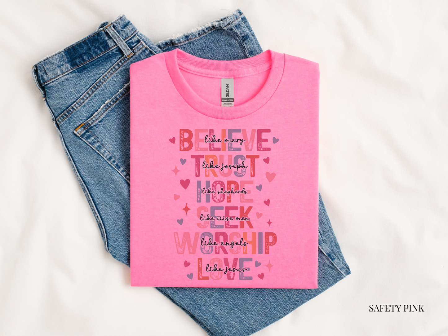 Pink t-shirt with colorful text design on blue jeans