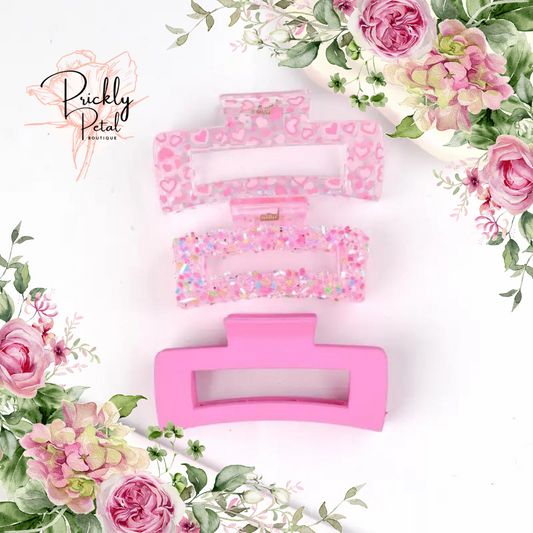 A set of pink hair clips with floral patterns, displayed on a white background surrounded by pink roses.