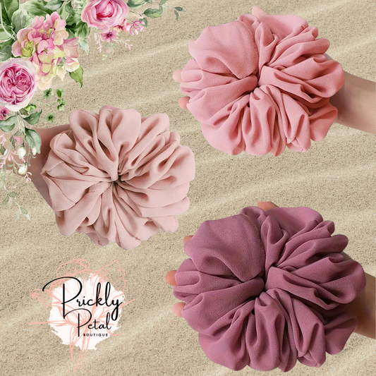 Three oversized chiffon scrunchies in pink, purple, and rose colors, displayed on a neutral background.