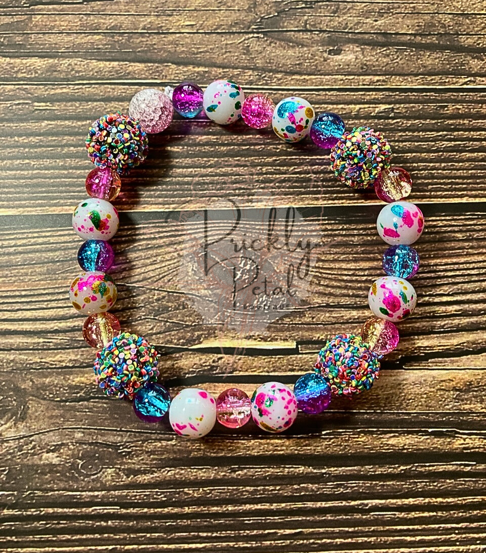 A beaded bracelet with a mix of solid and patterned beads in various colors displayed on a wooden surface.